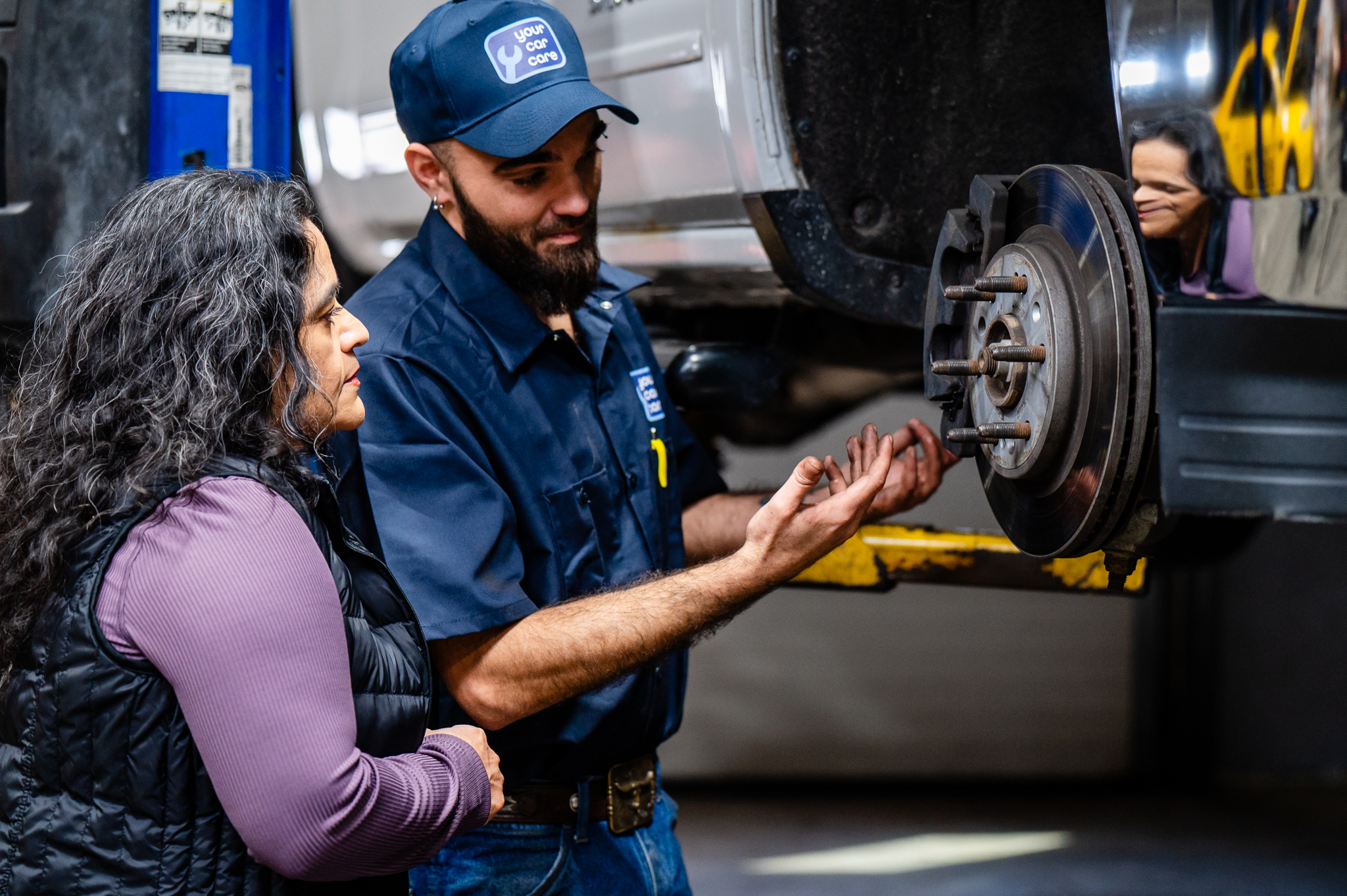 YCC technician explaining services to a customer while inspecting her vehicle