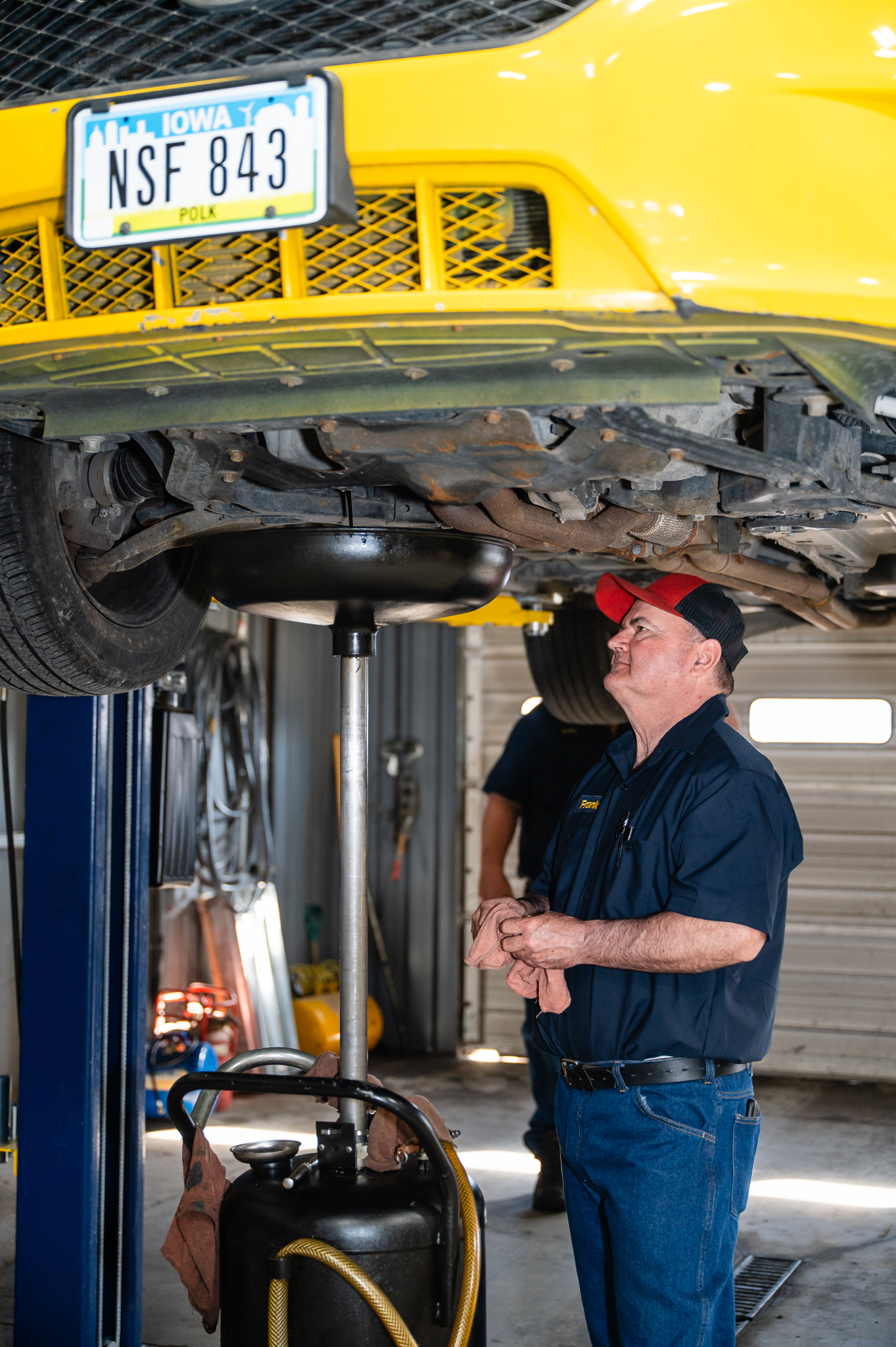 Mechanic inspecting the underside of a vehicle on a lift.