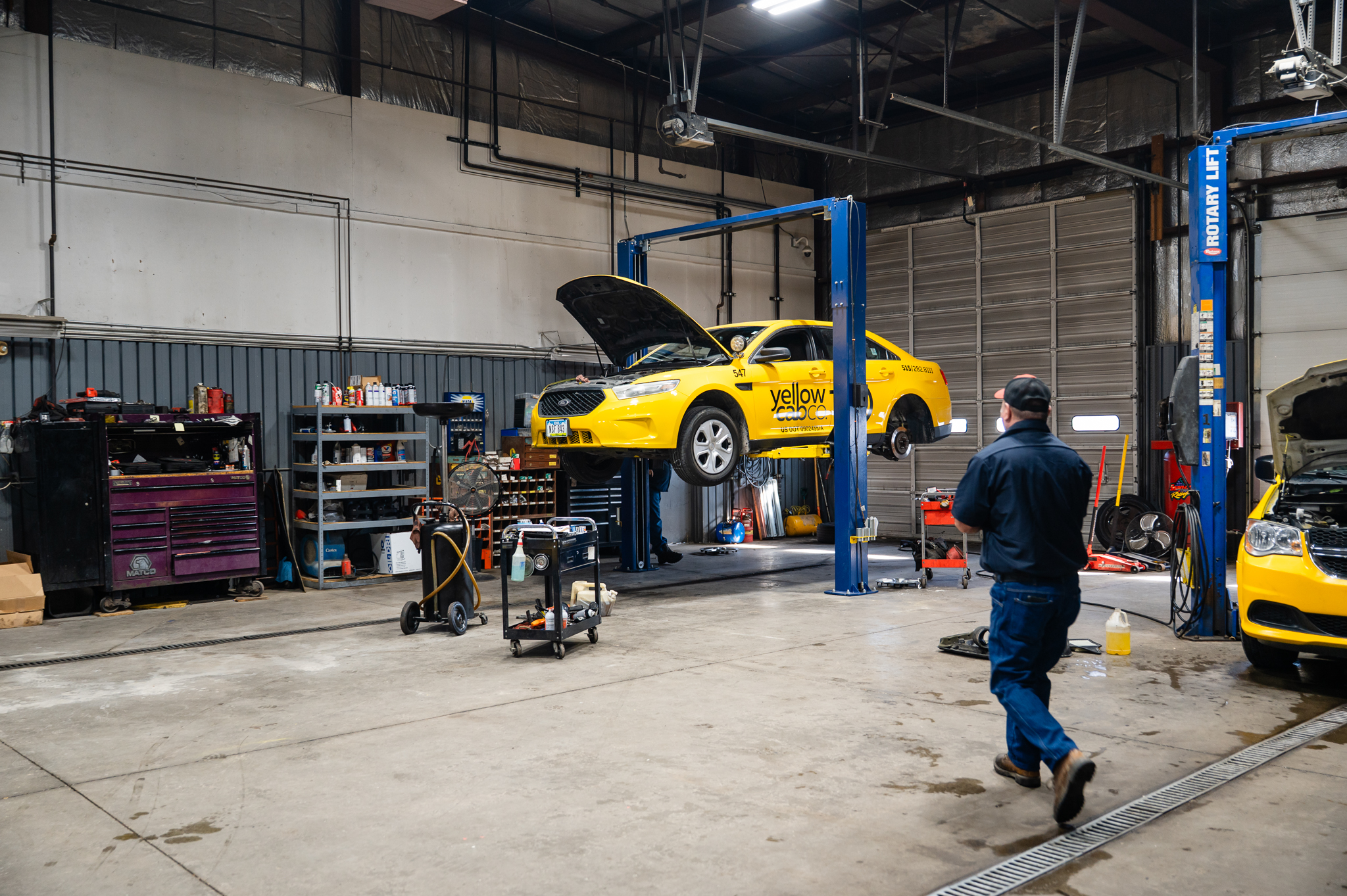 Auto technician approaching a vehicle on a lift to begin auto services